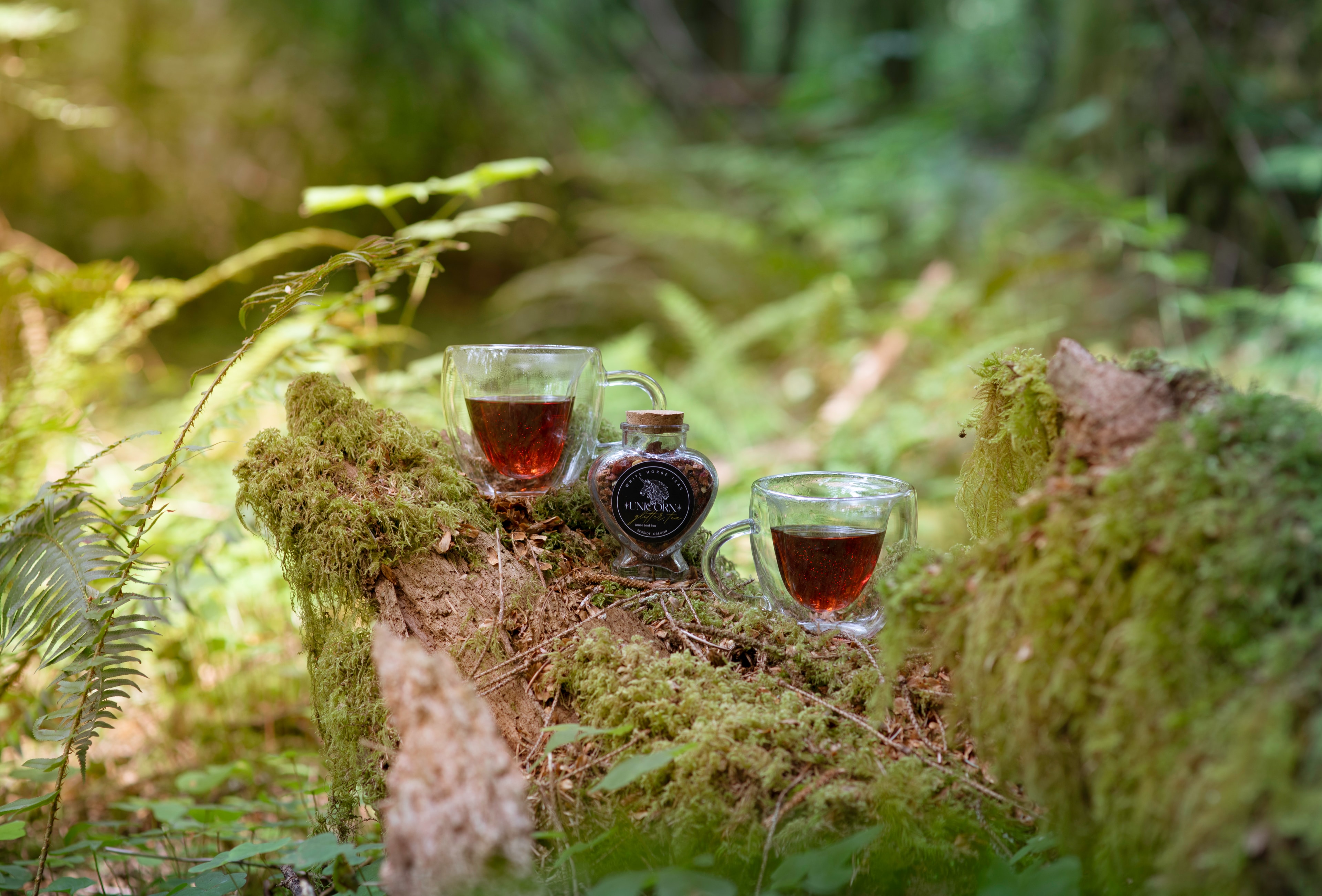 Two cups of tea and the heart jar on a mossy forest log